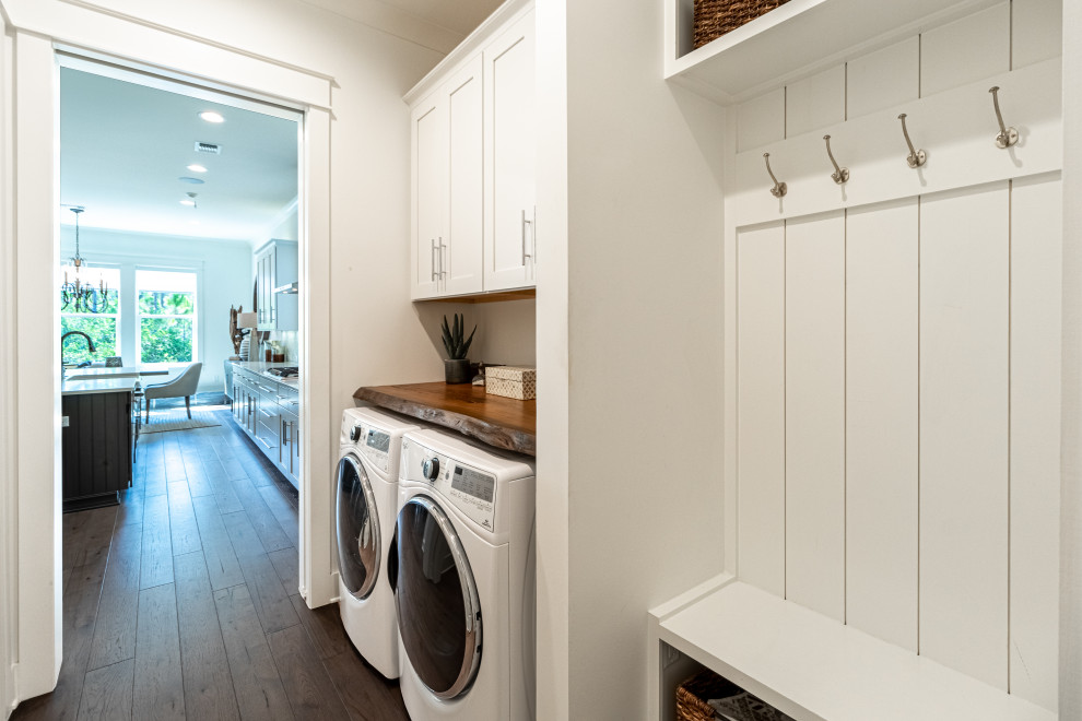Utility room - mid-sized traditional single-wall brown floor utility room idea in Miami with recessed-panel cabinets, white cabinets, wood countertops, white walls, a side-by-side washer/dryer and brown countertops
