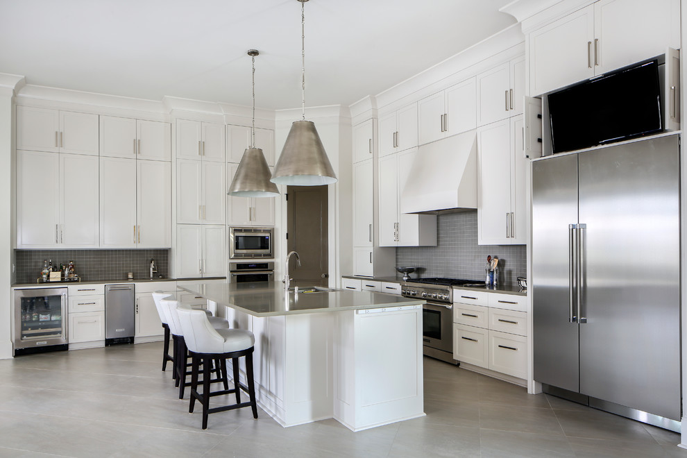 Inspiration for a large transitional l-shaped open plan kitchen in New Orleans with an undermount sink, shaker cabinets, yellow cabinets, grey splashback, glass tile splashback, stainless steel appliances, concrete floors and with island.