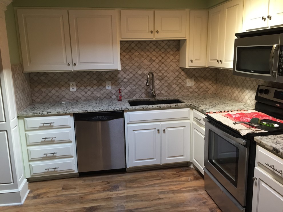 Modern inredning av ett litet kök, med en undermonterad diskho, luckor med upphöjd panel, vita skåp, bänkskiva i kvartsit, vitt stänkskydd, stänkskydd i stenkakel, rostfria vitvaror och tegelgolv