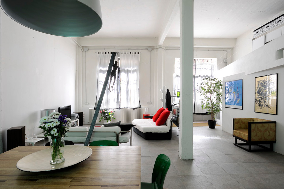 This is an example of a large industrial open concept living room in Milan with white walls and a freestanding tv.