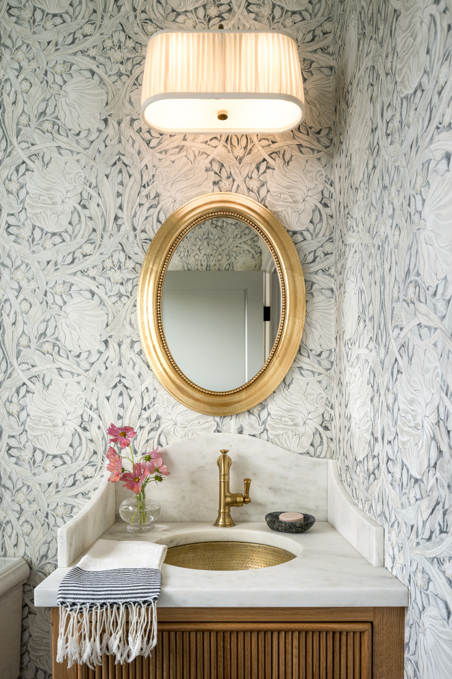 Example of a small transitional slate floor, black floor and wallpaper powder room design in Burlington with medium tone wood cabinets, a one-piece toilet, an undermount sink, marble countertops, white countertops and a built-in vanity