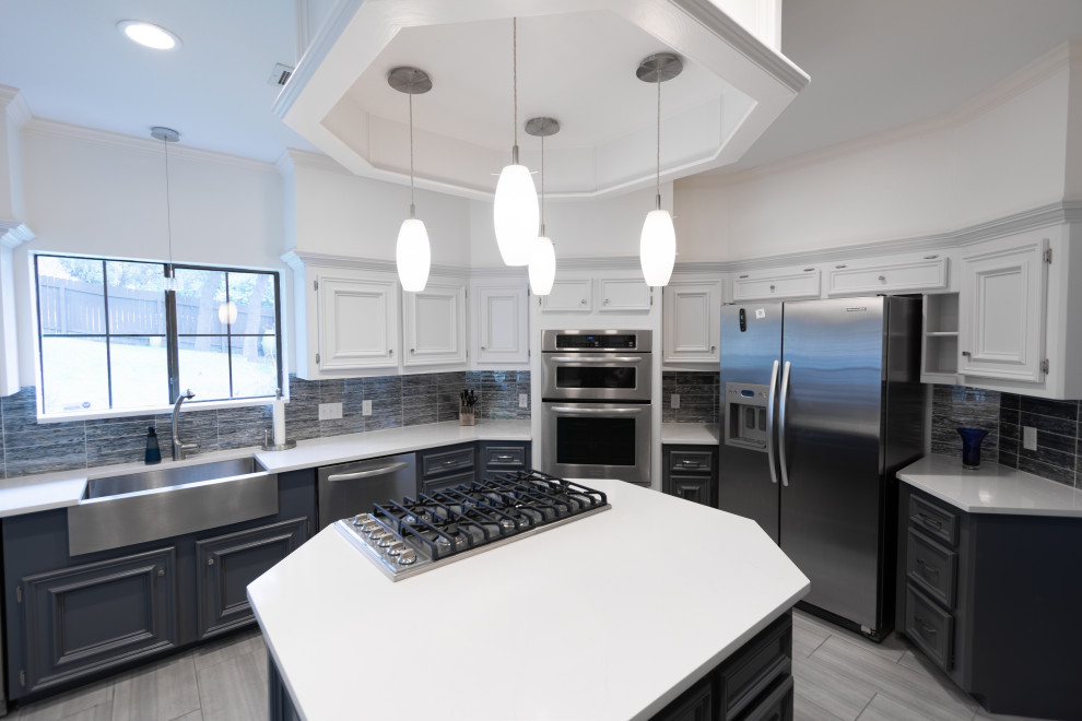 Mid-sized transitional u-shaped ceramic tile and gray floor enclosed kitchen photo in Austin with a farmhouse sink, recessed-panel cabinets, white cabinets, quartzite countertops, blue backsplash, glass tile backsplash, stainless steel appliances, an island and white countertops