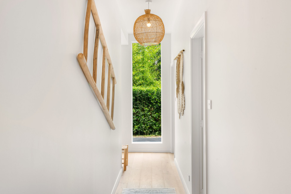 Inspiration for a mid-sized contemporary hallway in Sydney with white walls and light hardwood floors.