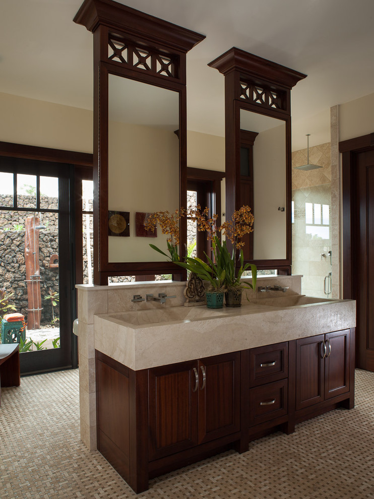 Large tropical bathroom in Hawaii with recessed-panel cabinets, dark wood cabinets, an alcove shower, a one-piece toilet, beige tile, stone tile, beige walls, porcelain floors, an integrated sink and granite benchtops.