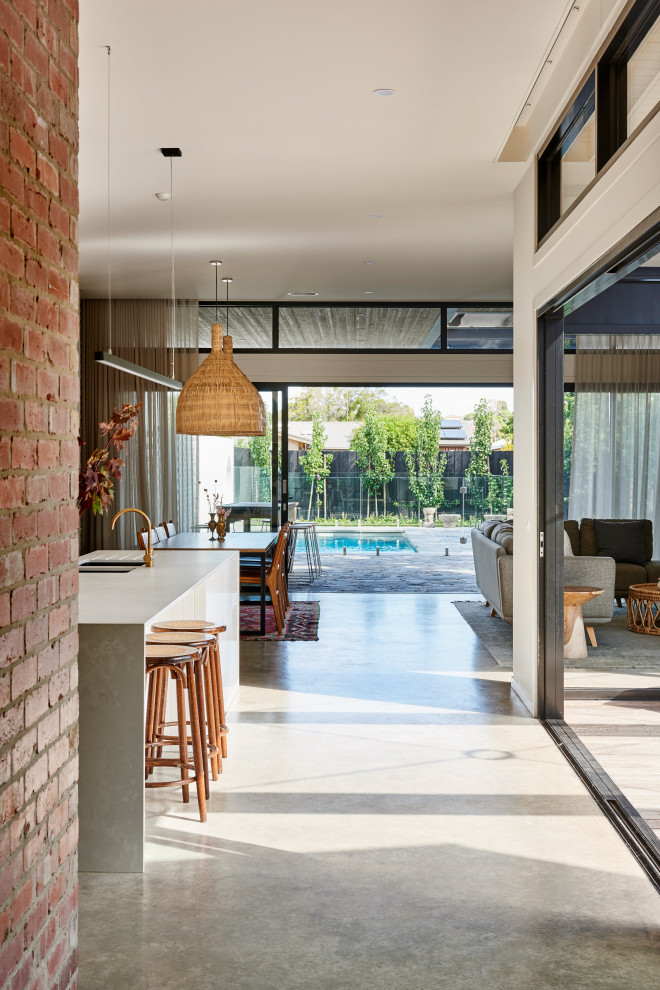 Inspiration for a large contemporary entry hall in Geelong with white walls, concrete floors, a single front door, a black front door, grey floor and brick walls.