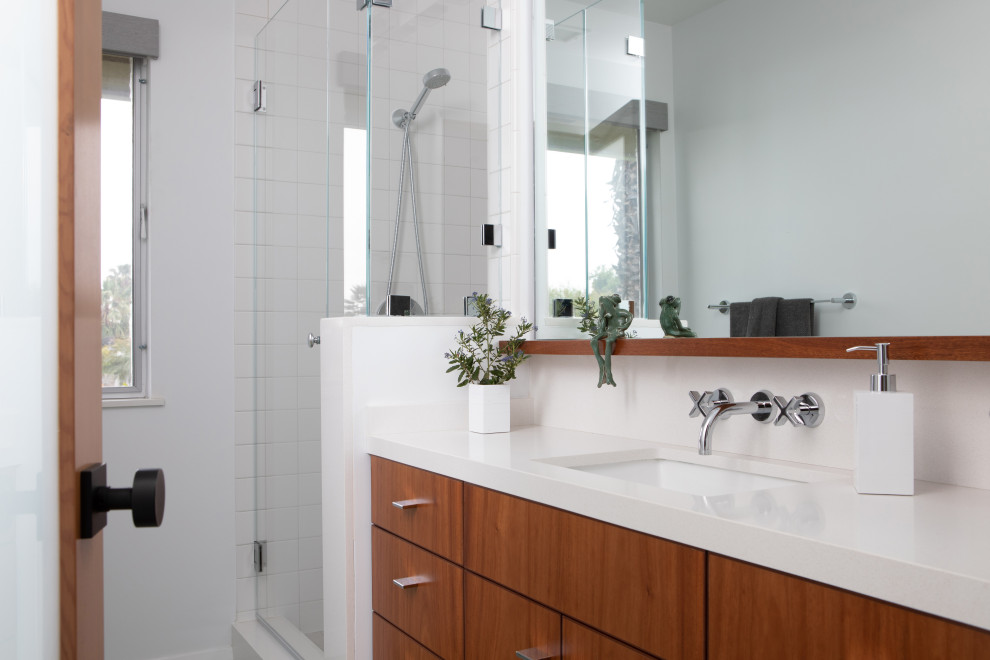 Photo of a small midcentury bathroom in Los Angeles with flat-panel cabinets, medium wood cabinets, a corner shower, white tile, ceramic tile, ceramic floors, an undermount sink, engineered quartz benchtops, a hinged shower door, white benchtops, a single vanity and a built-in vanity.