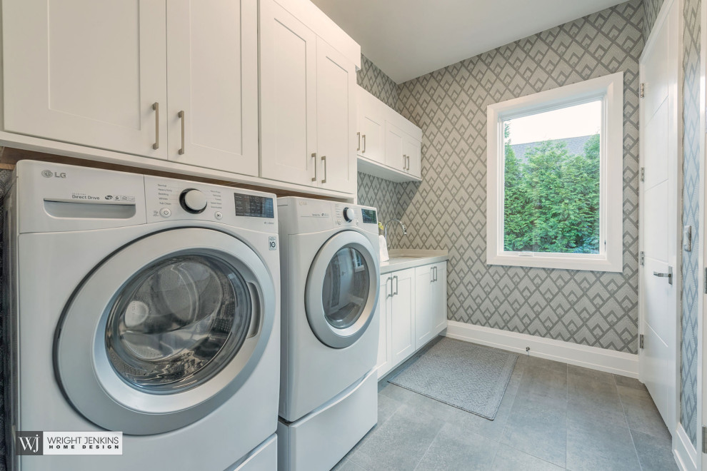 Photo of a large arts and crafts galley dedicated laundry room in Other with an undermount sink, recessed-panel cabinets, white cabinets, quartz benchtops, beige splashback, porcelain splashback, beige walls, slate floors, a side-by-side washer and dryer, grey floor, grey benchtop and wallpaper.