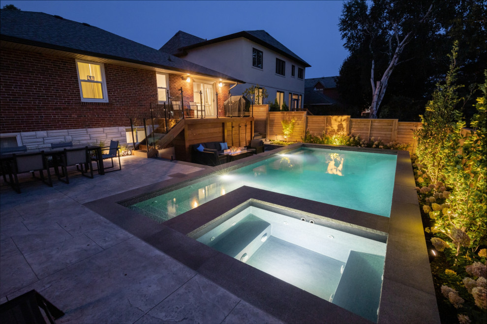 Foto di una piscina tradizionale rettangolare di medie dimensioni e dietro casa con paesaggistica bordo piscina e cemento stampato