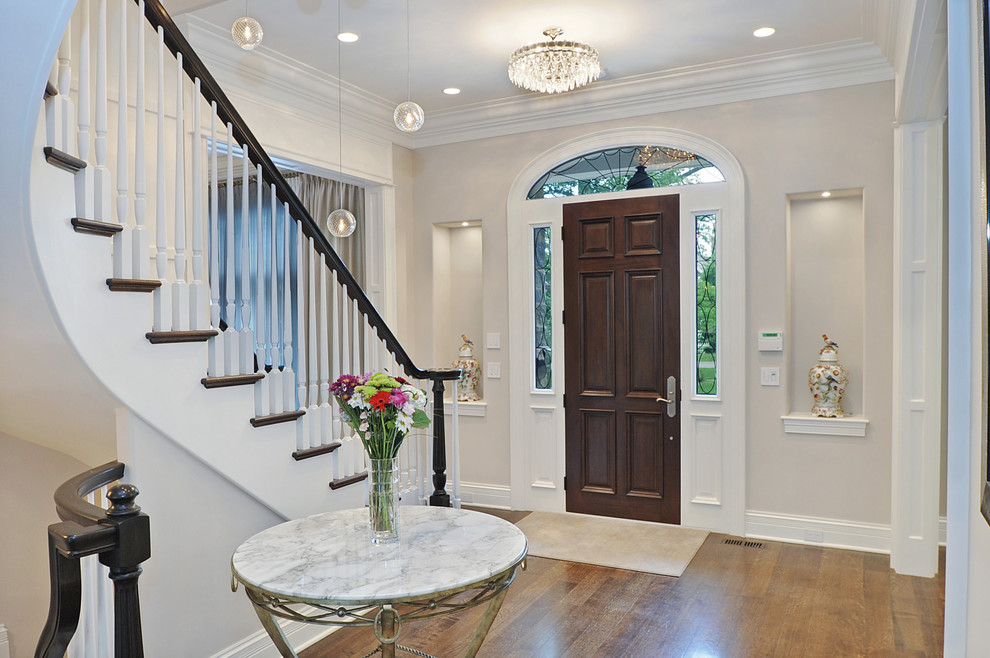 This is an example of a traditional entryway in Chicago with a dark wood front door and grey walls.