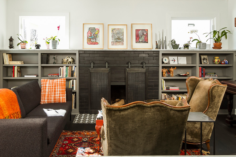 Design ideas for an eclectic living room in Minneapolis with white walls, dark hardwood floors, a standard fireplace, a brick fireplace surround and a library.