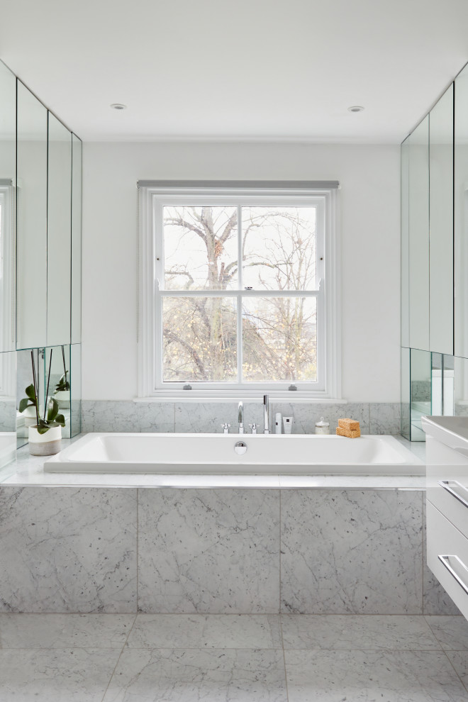 Réalisation d'une salle de bain design avec une baignoire posée, un carrelage gris, un mur blanc et un sol gris.