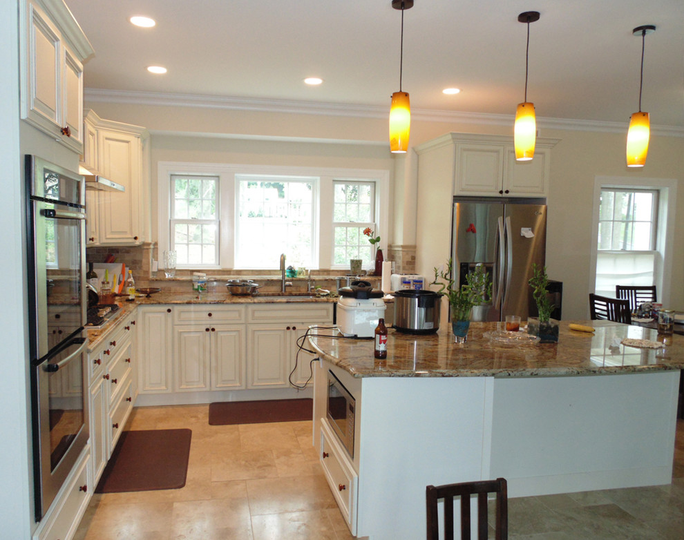 This is an example of a large traditional l-shaped eat-in kitchen in New York with an undermount sink, raised-panel cabinets, white cabinets, granite benchtops, beige splashback, ceramic splashback, stainless steel appliances, ceramic floors, with island and beige floor.