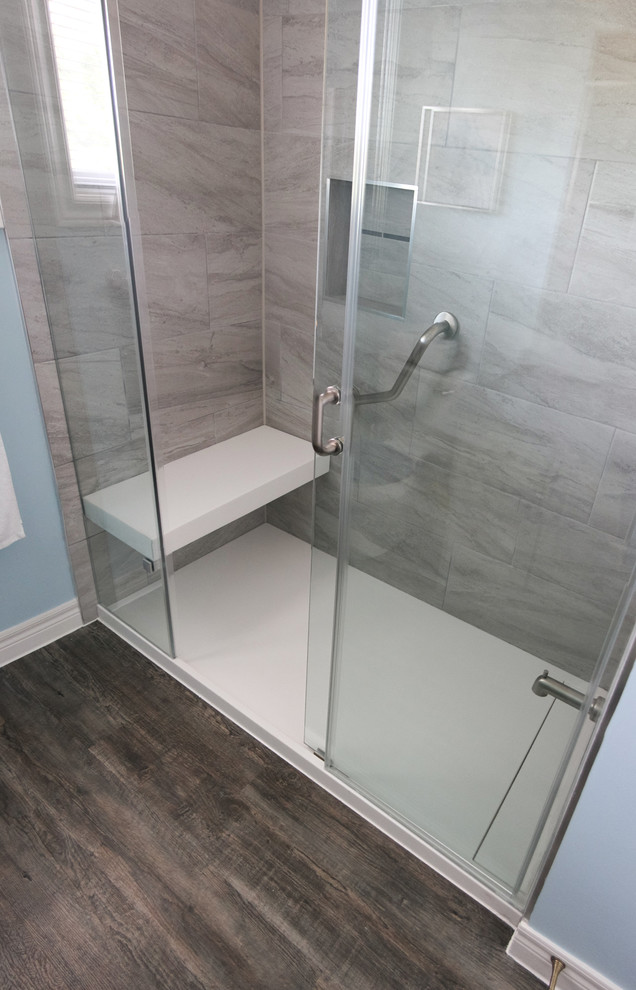 This is an example of a mid-sized contemporary 3/4 bathroom in Toronto with glass-front cabinets, gray tile, porcelain tile and solid surface benchtops.