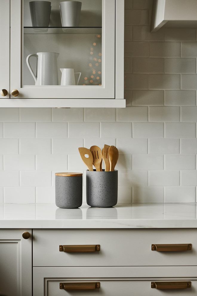 Mid-sized transitional u-shaped light wood floor and beige floor eat-in kitchen photo with a farmhouse sink, white backsplash, an island, white countertops, recessed-panel cabinets, beige cabinets, marble countertops, subway tile backsplash and paneled appliances