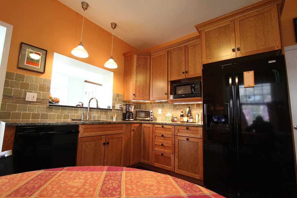 Inspiration for a mid-sized timeless dark wood floor eat-in kitchen remodel in Philadelphia with an undermount sink, shaker cabinets, medium tone wood cabinets, granite countertops, stone tile backsplash and black appliances