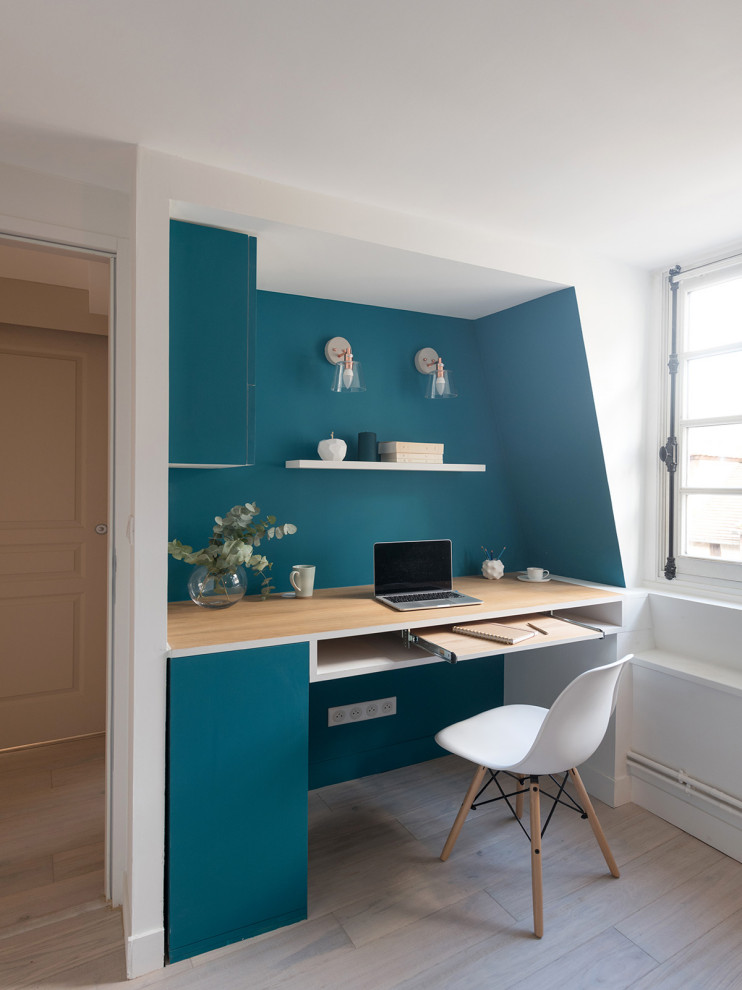 Inspiration for a small contemporary study room in Other with blue walls, light hardwood floors, a freestanding desk and beige floor.