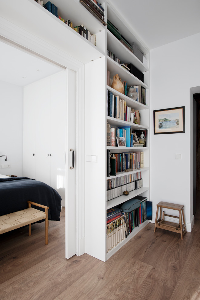 Idee per uno studio scandinavo di medie dimensioni con libreria, pareti bianche, pavimento in laminato, scrivania incassata, pavimento marrone e travi a vista