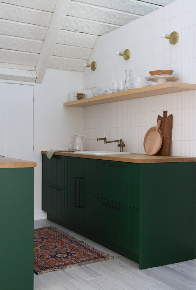 Design ideas for a small country galley separate kitchen in Los Angeles with a drop-in sink, beaded inset cabinets, green cabinets, wood benchtops, white splashback, ceramic splashback, black appliances, no island, grey floor and brown benchtop.