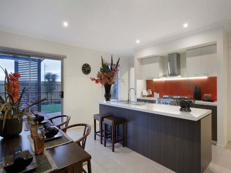 Design ideas for a mid-sized contemporary kitchen in Melbourne with a double-bowl sink, dark wood cabinets, solid surface benchtops, red splashback, glass sheet splashback, stainless steel appliances, porcelain floors and with island.