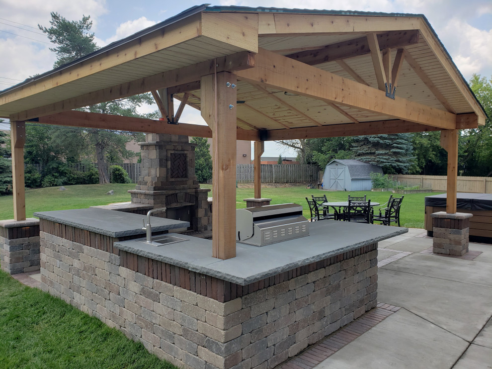 Photo of a medium sized classic back patio in Milwaukee with an outdoor kitchen, concrete slabs and a pergola.