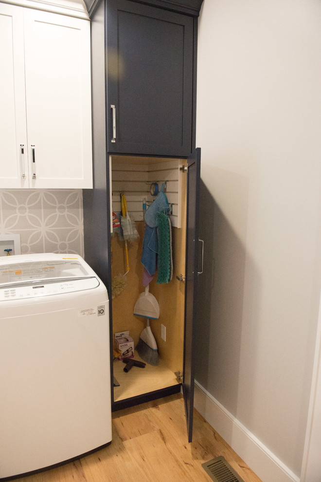Large transitional u-shaped light wood floor home design photo with shaker cabinets, blue cabinets, quartz countertops, gray walls, a side-by-side washer/dryer and white countertops