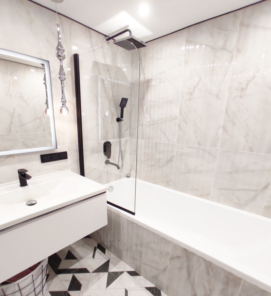 Идея дизайна: маленькая главная, серо-белая ванная комната со стиральной машиной в современном стиле с плоскими фасадами, серыми фасадами, полновстраиваемой ванной, инсталляцией, белой плиткой, мраморной плиткой, белыми стенами, полом из керамогранита, монолитной раковиной, столешницей из искусственного камня, черным полом, белой столешницей, тумбой под одну раковину и подвесной тумбой для на участке и в саду