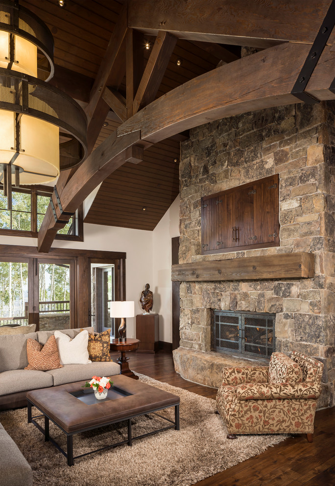 Inspiration for a large country open concept family room in Salt Lake City with a game room, white walls, medium hardwood floors, a standard fireplace, a stone fireplace surround, a concealed tv and brown floor.