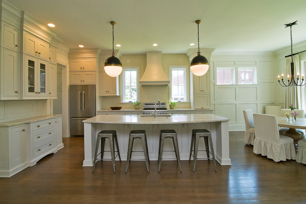 This is an example of a mid-sized country l-shaped eat-in kitchen in Raleigh with an undermount sink, shaker cabinets, white cabinets, marble benchtops, white splashback, subway tile splashback, stainless steel appliances, dark hardwood floors, with island and brown floor.