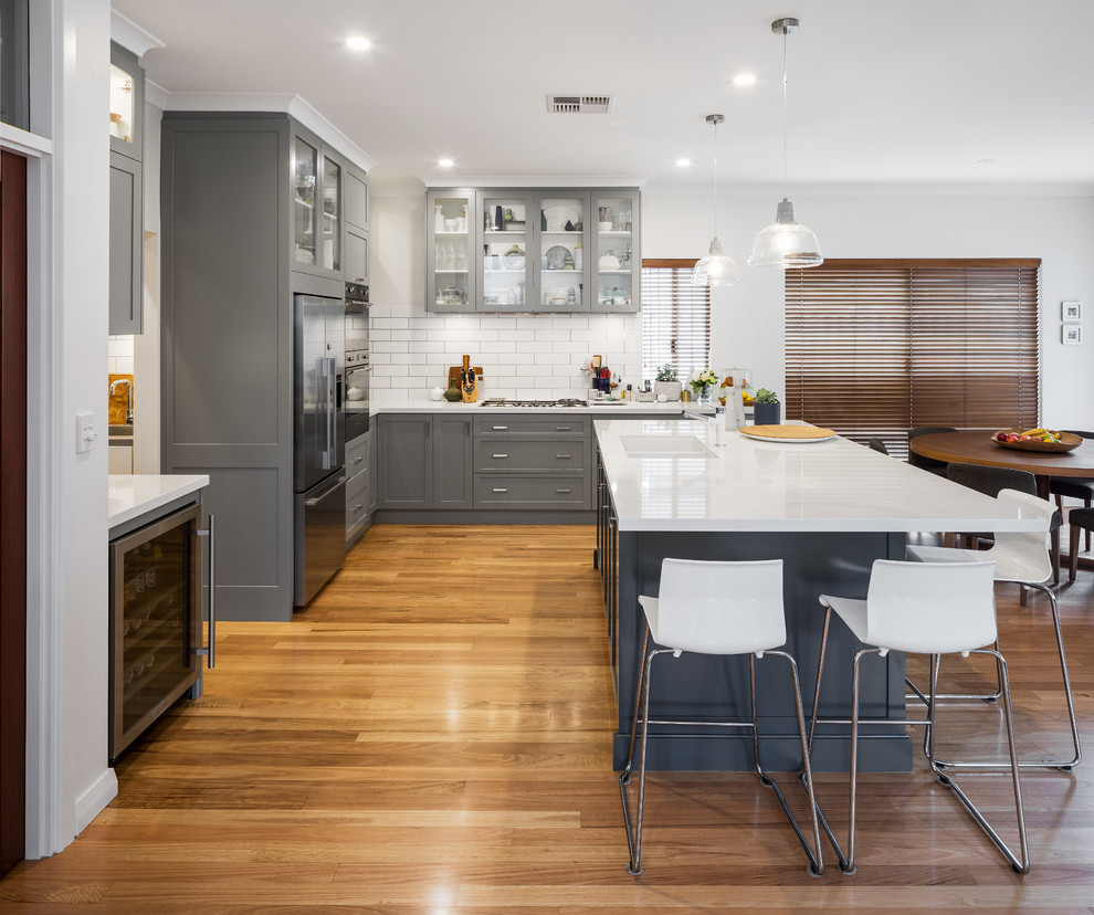 Inspiration for a transitional kitchen in Perth with an undermount sink, shaker cabinets, grey cabinets, quartz benchtops, white splashback, subway tile splashback, stainless steel appliances, with island, white benchtop and light hardwood floors.