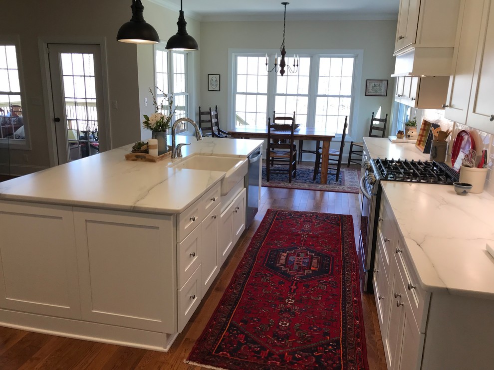 Design ideas for a large transitional galley eat-in kitchen in Other with a farmhouse sink, shaker cabinets, white cabinets, marble benchtops, white splashback, subway tile splashback, stainless steel appliances, medium hardwood floors, with island, brown floor and white benchtop.