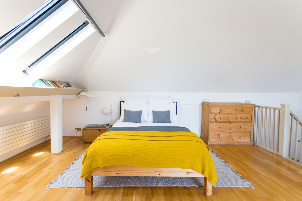 This is an example of a scandinavian loft-style bedroom in London with white walls, medium hardwood floors and no fireplace.
