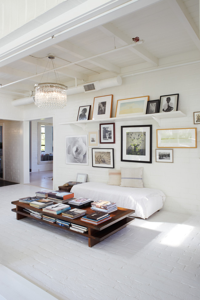 Inspiration for a mid-sized industrial family room in Orange County with white walls, brick floors and no fireplace.