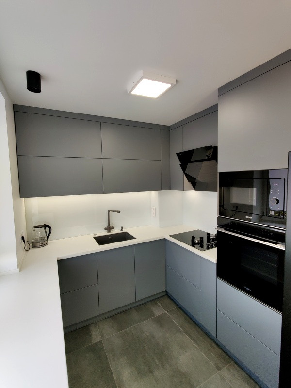 Photo of a medium sized contemporary grey and white u-shaped enclosed kitchen in Moscow with a single-bowl sink, flat-panel cabinets, grey cabinets, composite countertops, white splashback, ceramic splashback, integrated appliances, ceramic flooring, no island, brown floors and white worktops.