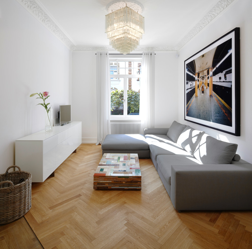 This is an example of a mid-sized modern formal enclosed living room in Frankfurt with white walls, light hardwood floors, no fireplace and a freestanding tv.