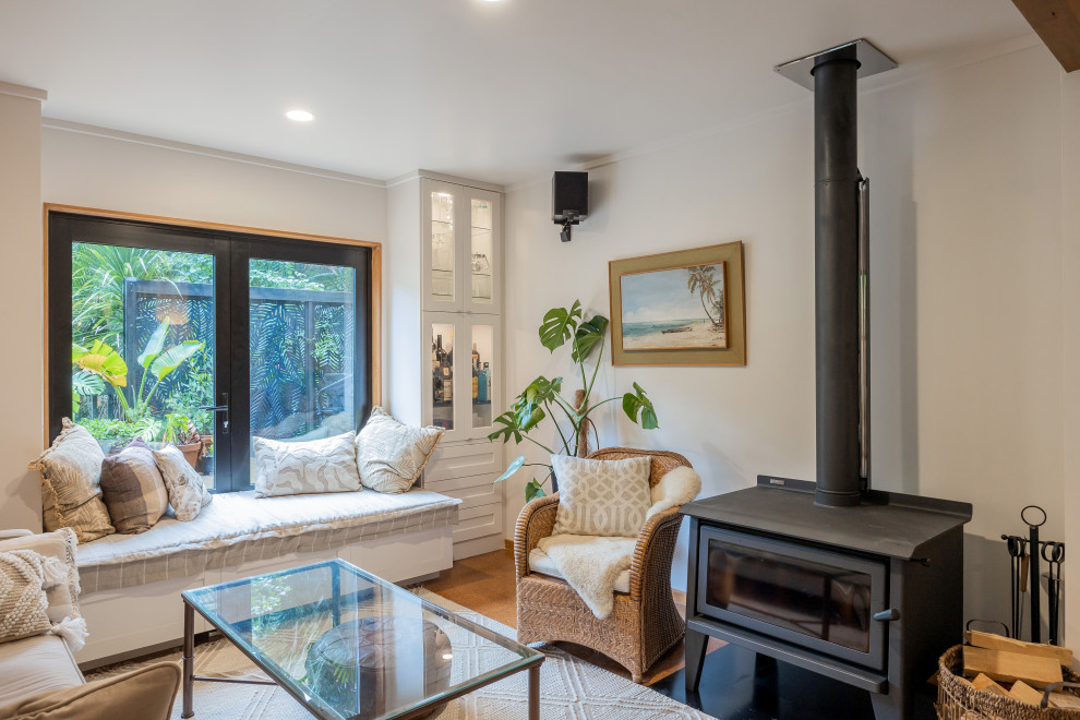 Immagine di un piccolo soggiorno eclettico aperto con pareti bianche, pavimento in sughero, stufa a legna e pavimento marrone