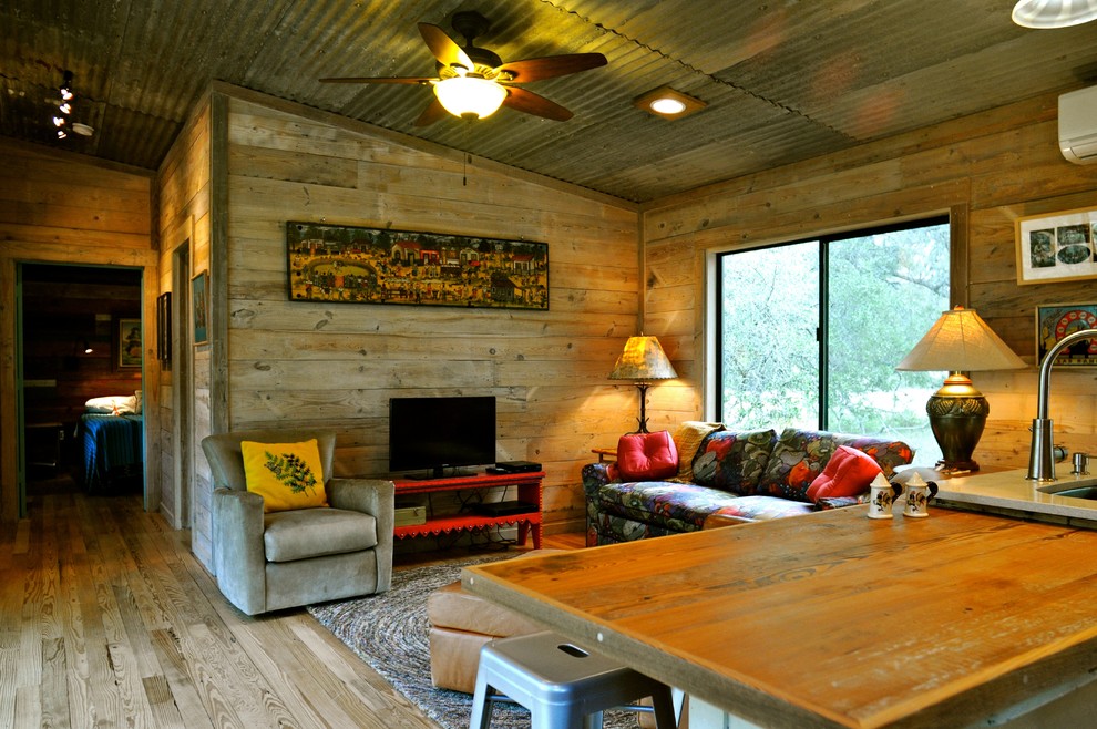 Example of a mountain style medium tone wood floor living room design in Austin with a tv stand
