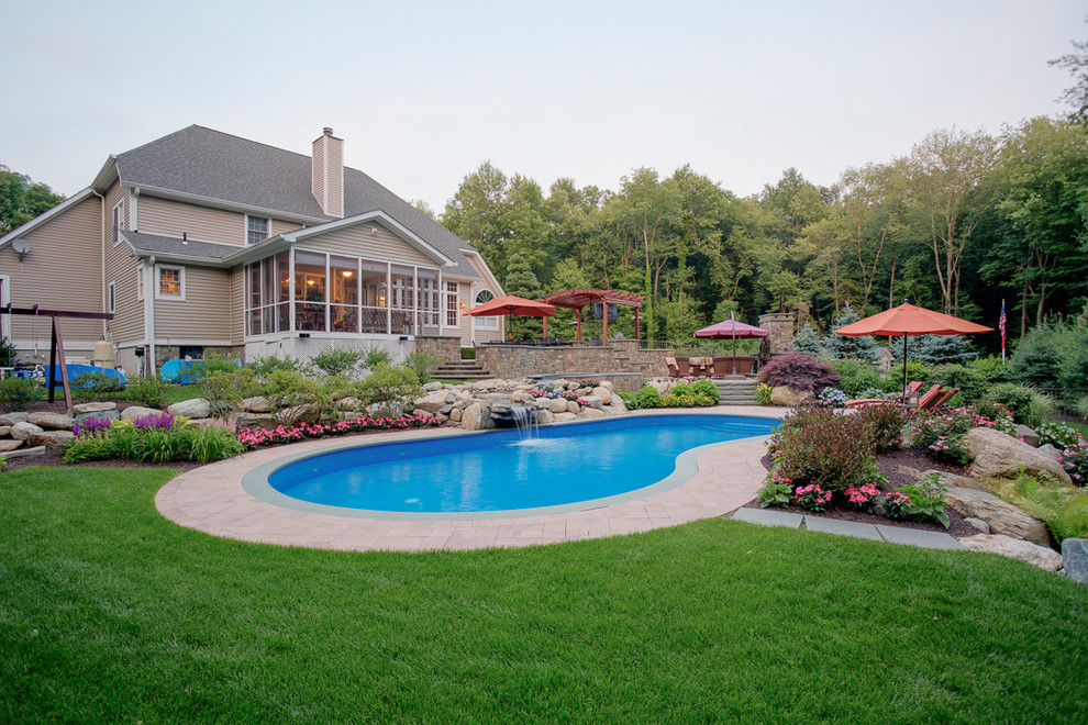 This is an example of a large contemporary backyard kidney-shaped lap pool in New York with a hot tub and concrete pavers.