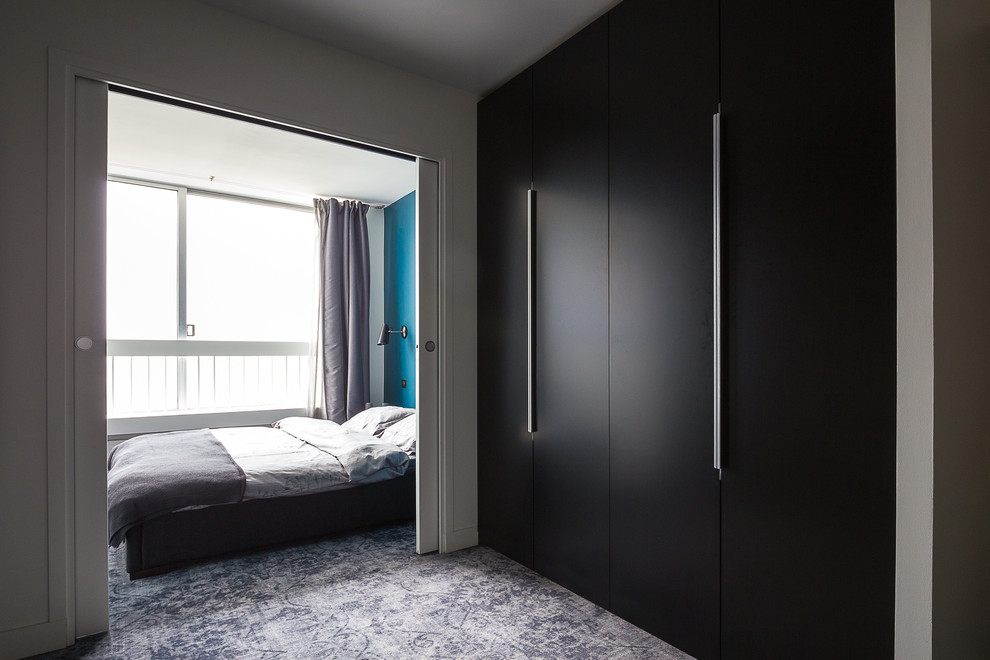 This is an example of a large contemporary gender-neutral dressing room in Paris with dark wood cabinets, carpet and flat-panel cabinets.