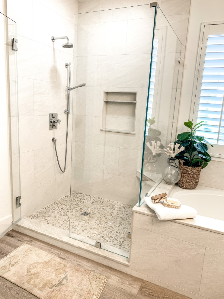 Photo of a mid-sized beach style master bathroom in Orange County with shaker cabinets, white cabinets, an undermount tub, a corner shower, beige tile, porcelain tile, white walls, light hardwood floors, a drop-in sink, quartzite benchtops, a hinged shower door, beige benchtops, a shower seat, a double vanity and a built-in vanity.