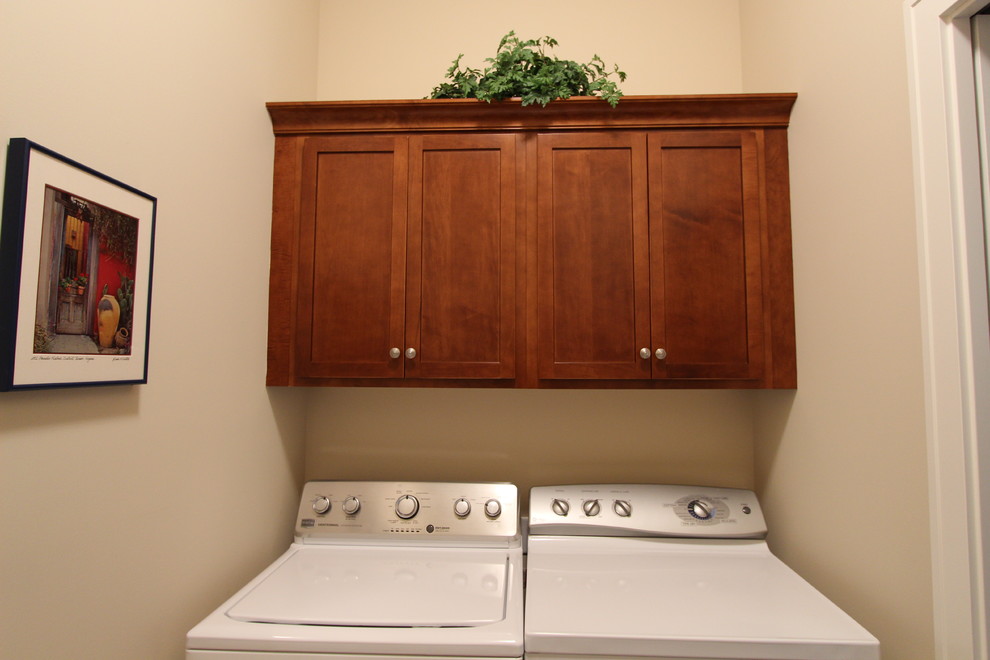 Small transitional single-wall laundry cupboard in Grand Rapids with recessed-panel cabinets, quartz benchtops, multi-coloured splashback, a drop-in sink, dark wood cabinets, beige walls, linoleum floors and a side-by-side washer and dryer.