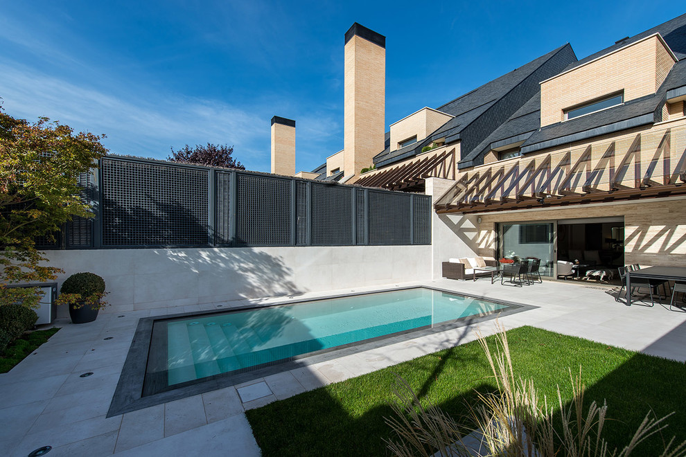 Inspiration for a mid-sized contemporary backyard rectangular lap pool in Madrid with a pool house and tile.