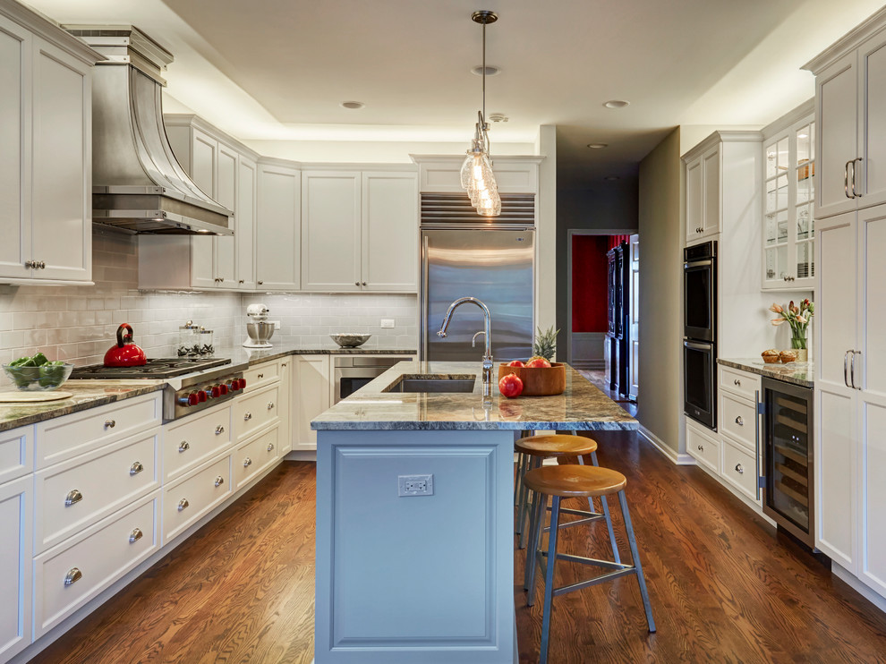 Example of a transitional dark wood floor and brown floor kitchen design in Chicago with an undermount sink, shaker cabinets, white cabinets, gray backsplash, stainless steel appliances, a peninsula and gray countertops