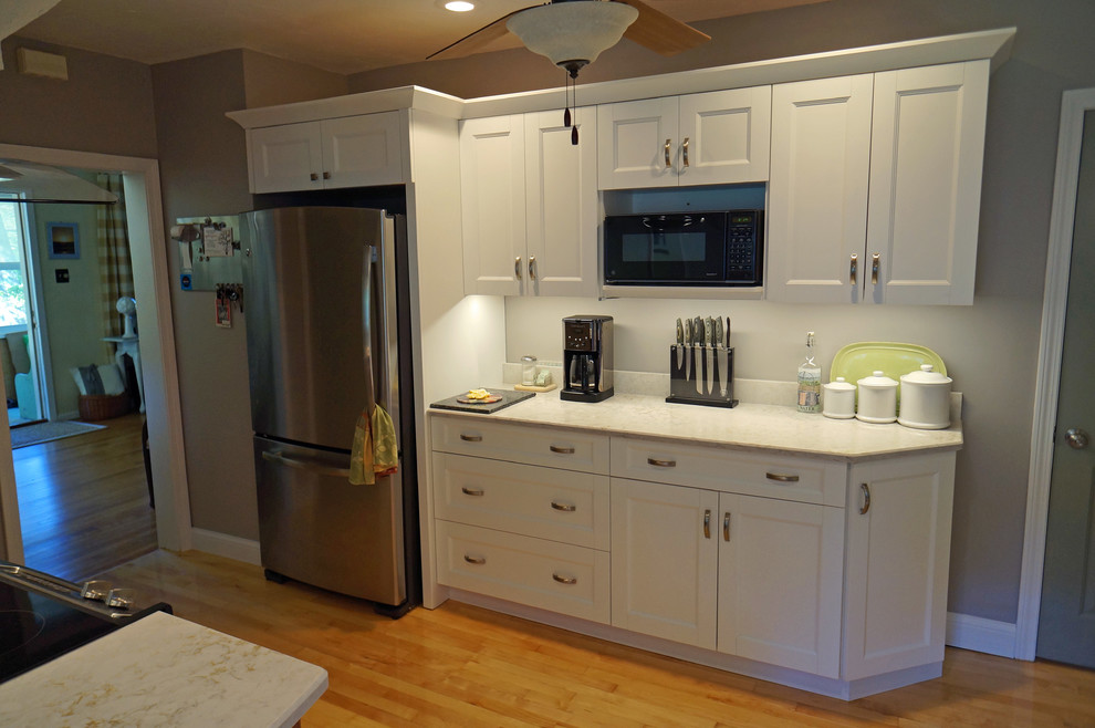 Eat-in kitchen - large transitional l-shaped light wood floor eat-in kitchen idea in Boston with a farmhouse sink, shaker cabinets, white cabinets, quartz countertops, white backsplash, stone slab backsplash, stainless steel appliances and an island