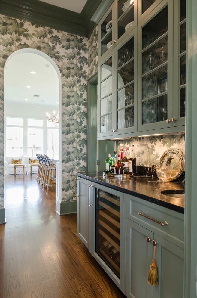 Inspiration for a mid-sized traditional single-wall wet bar in New Orleans with an undermount sink, raised-panel cabinets, green cabinets, marble benchtops, black splashback and dark hardwood floors.