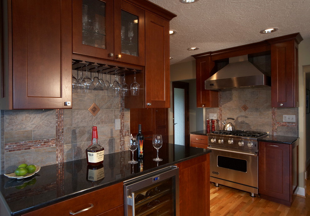 Mid-sized transitional l-shaped light wood floor and beige floor open concept kitchen photo in Seattle with an undermount sink, raised-panel cabinets, medium tone wood cabinets, granite countertops, metallic backsplash, ceramic backsplash, stainless steel appliances and no island