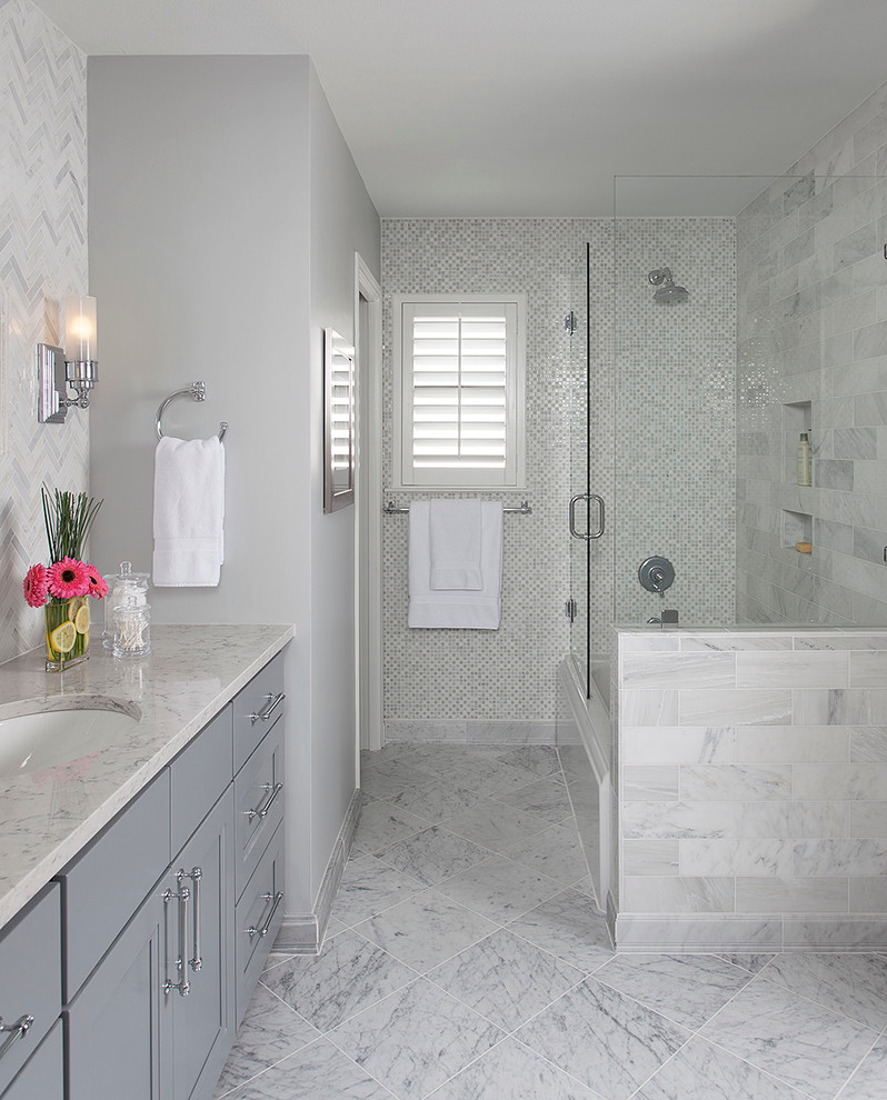 This is an example of a small transitional 3/4 bathroom in Austin with shaker cabinets, grey cabinets, an alcove tub, a shower/bathtub combo, gray tile, grey walls, marble floors, an undermount sink, engineered quartz benchtops, stone tile, a one-piece toilet, white floor, a hinged shower door and white benchtops.
