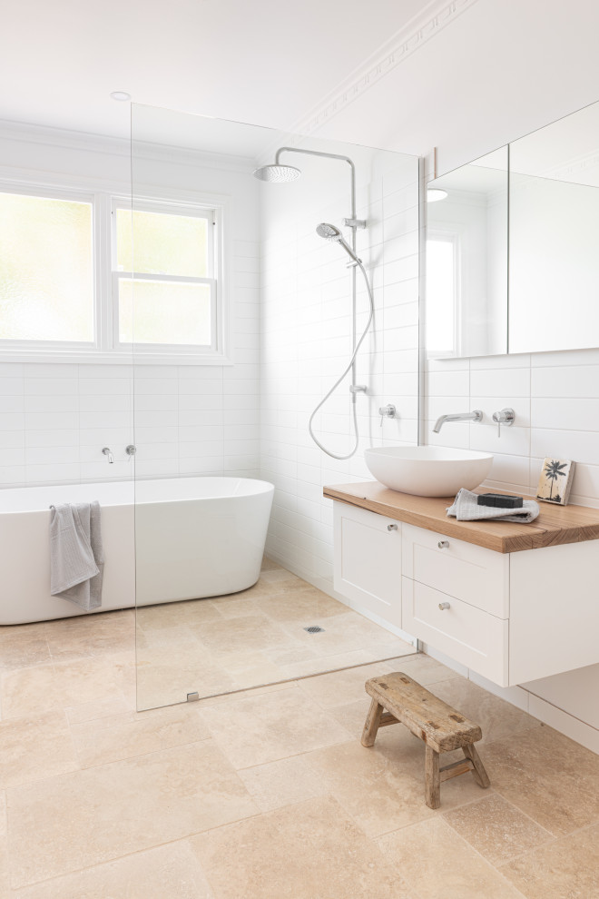 This is an example of a contemporary wet room bathroom in Geelong with shaker cabinets, white cabinets, a freestanding tub, white tile, white walls, a vessel sink, wood benchtops, beige floor and beige benchtops.