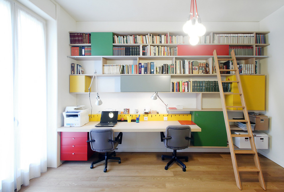 This is an example of a modern home office in Milan with white walls, light hardwood floors and a built-in desk.