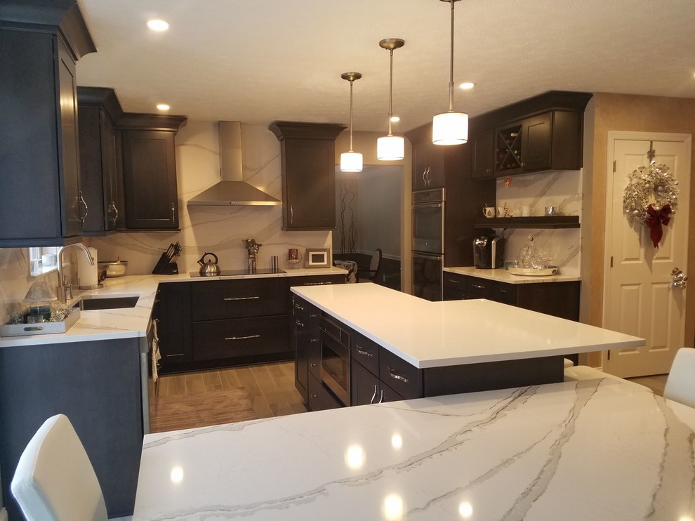 Inspiration for a mid-sized transitional l-shaped porcelain tile and gray floor enclosed kitchen remodel with an undermount sink, raised-panel cabinets, dark wood cabinets, quartz countertops, white backsplash, stone slab backsplash, stainless steel appliances and an island