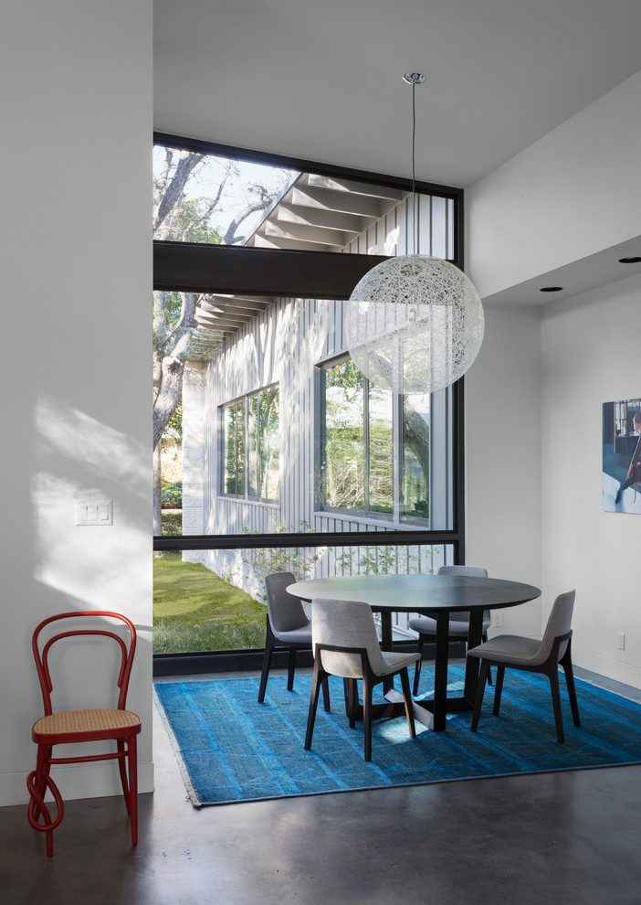 Inspiration for a midcentury dining room in Austin with white walls and concrete floors.